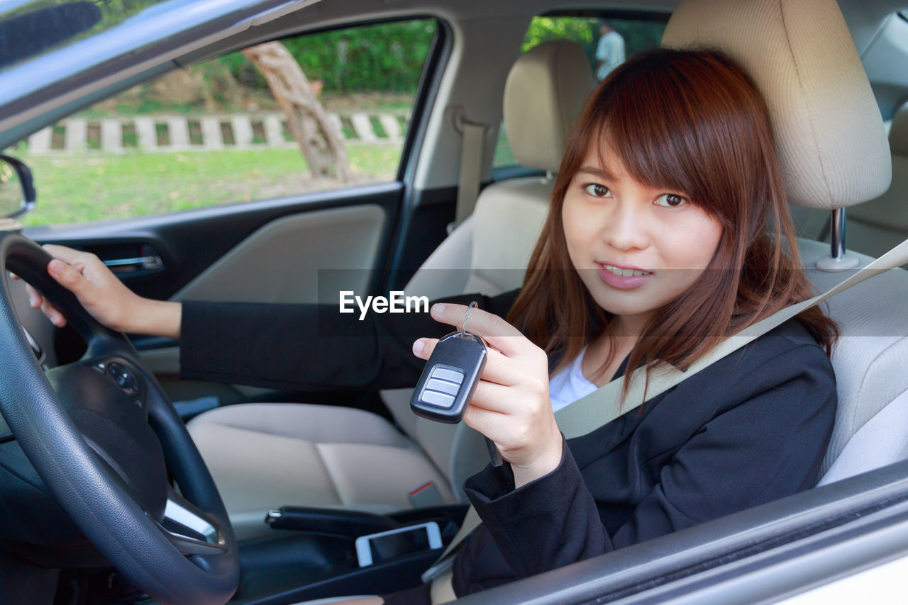 Portrait of smiling businesswoman holding key while sitting in car