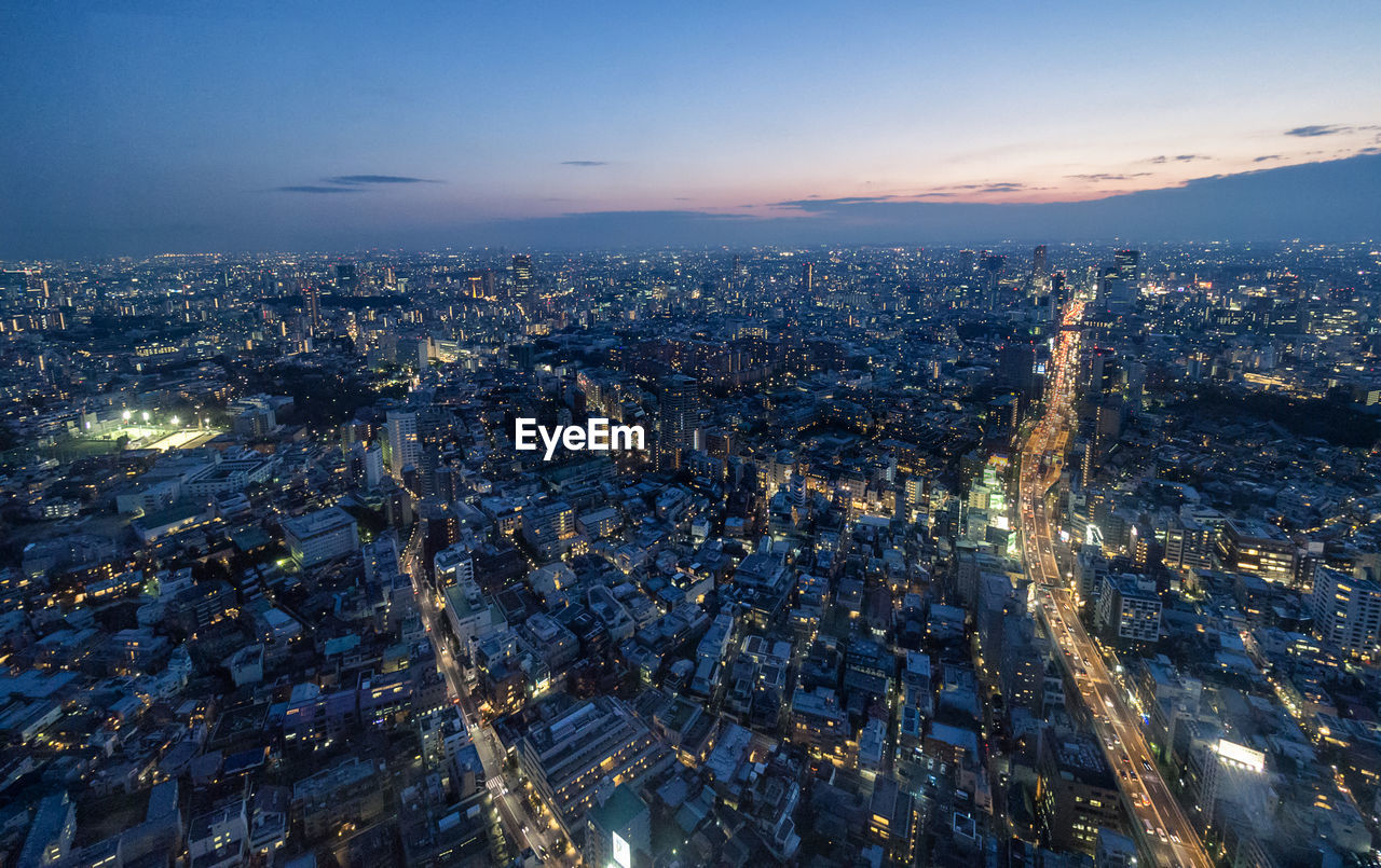 Illuminated cityscape against sky at dusk