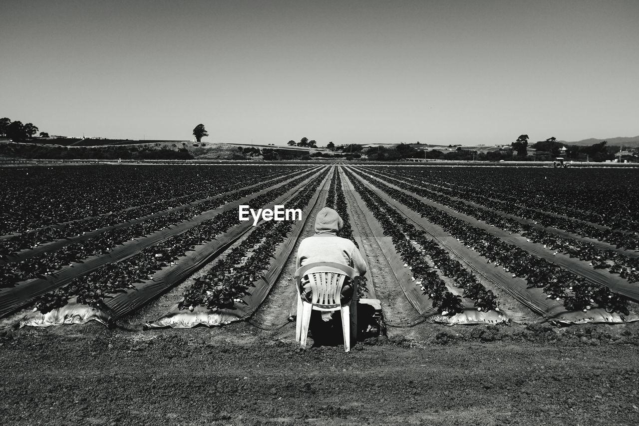 Person sitting in plastic chair in field