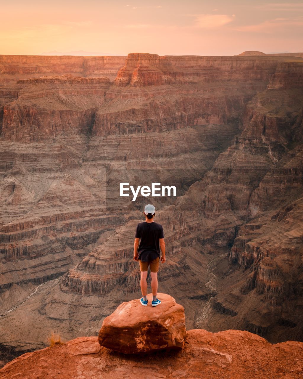 Rear view of man standing on rock at grand canyon during sunset