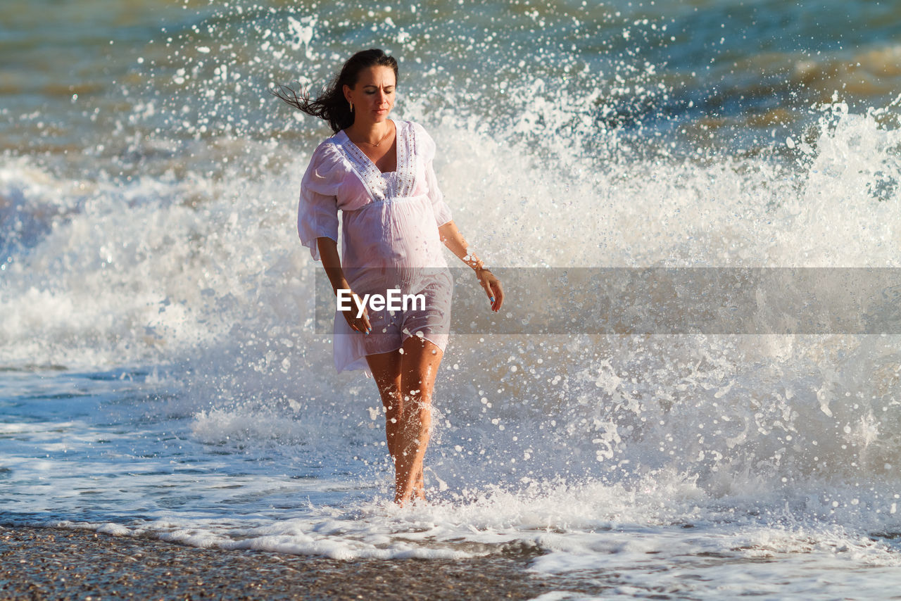 Pregnant woman is jumping on beach. cheerful pregnant woman runs on seashore.