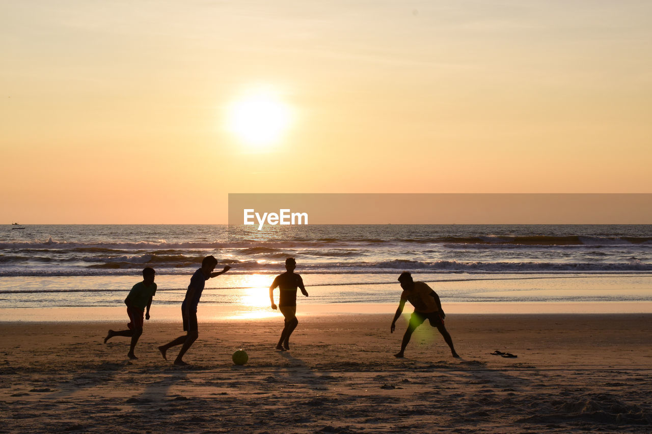 Silhouette people on beach against sky during sunset