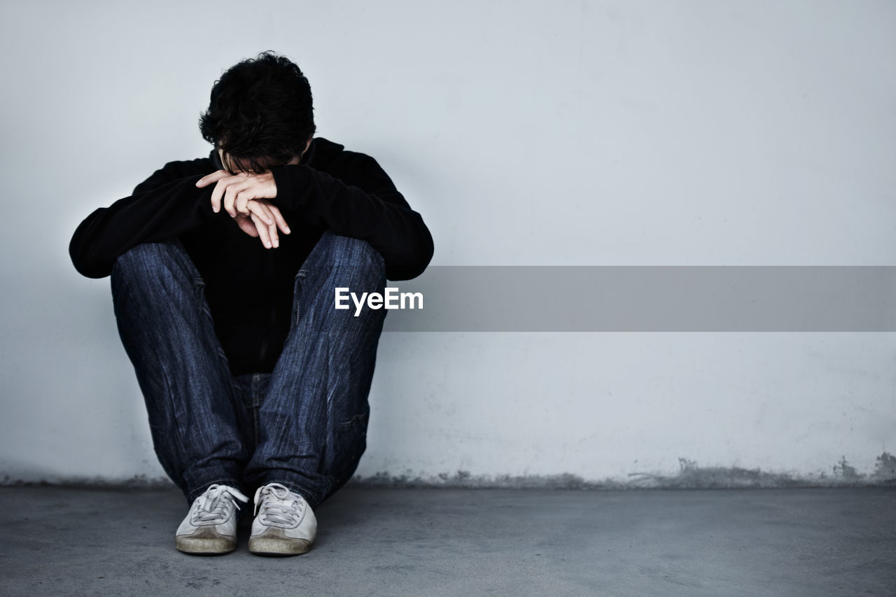 A man looking sad and depressed. a young guy sitting on the floor. mental health and emotion