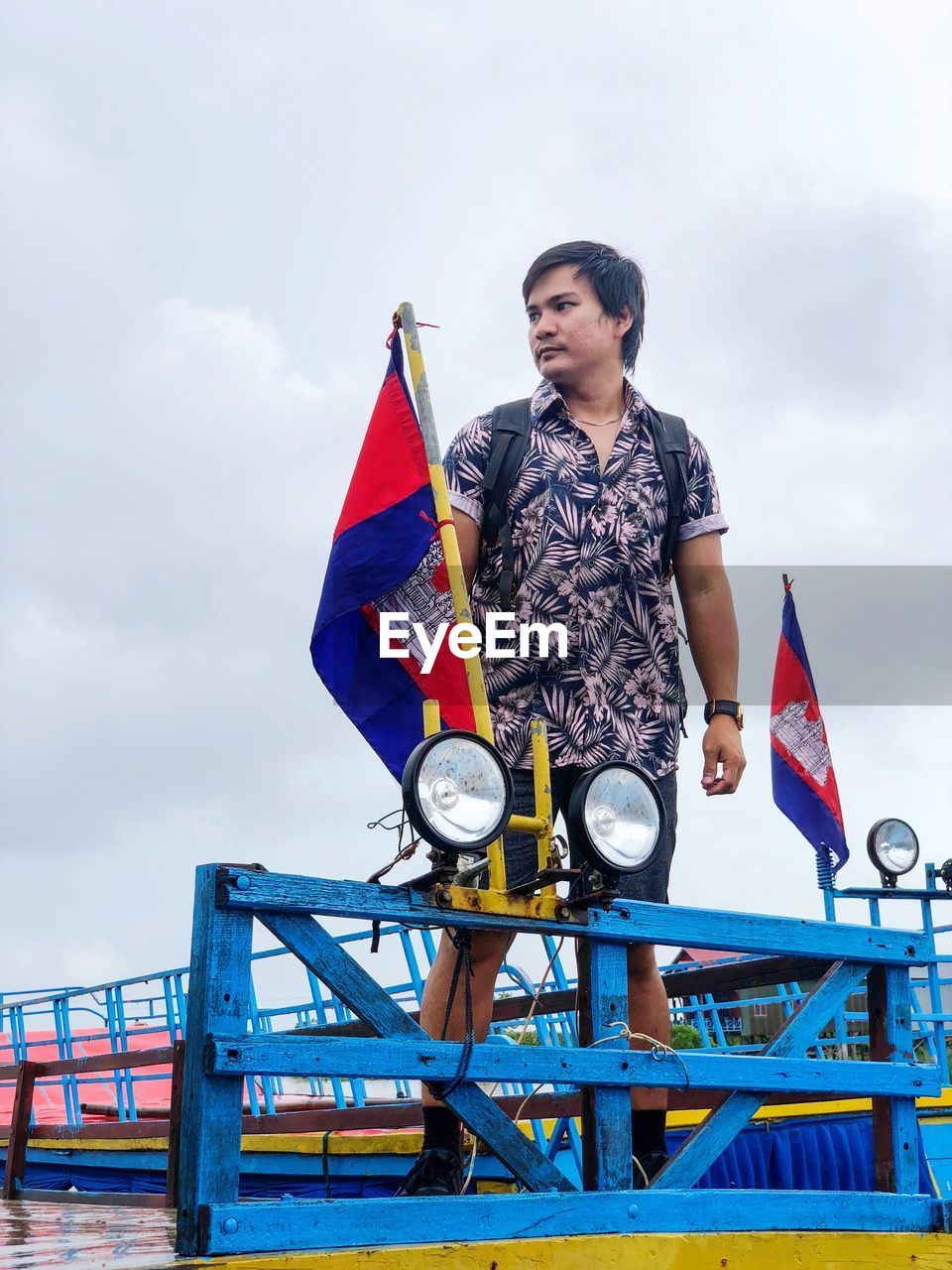 Low angle view of man standing on boat against sky