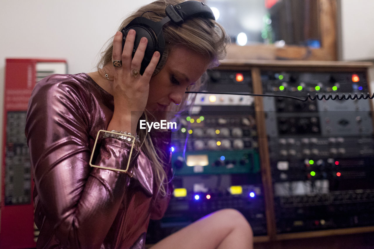 Young woman listening to music through large headphones