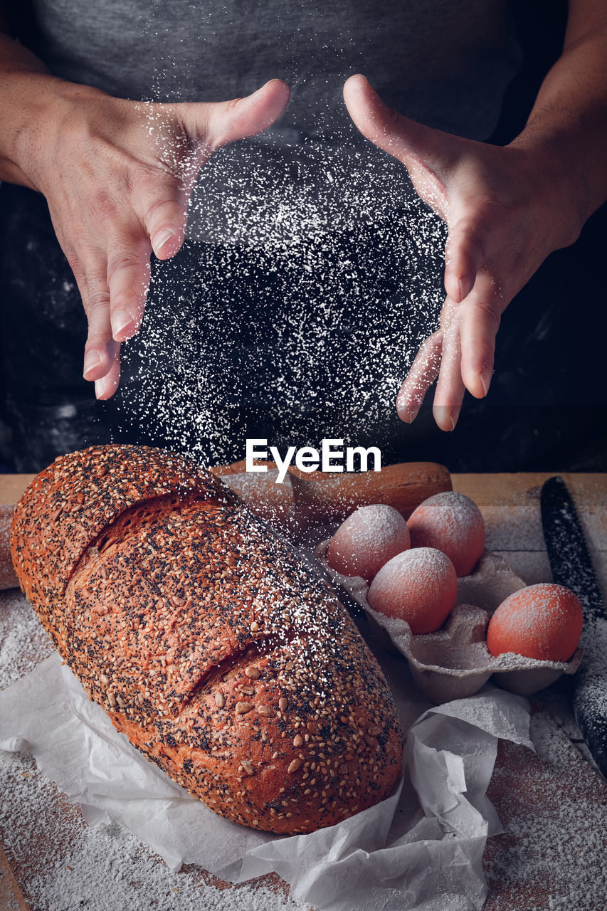 Baker's man spraying flour on bread and eggs