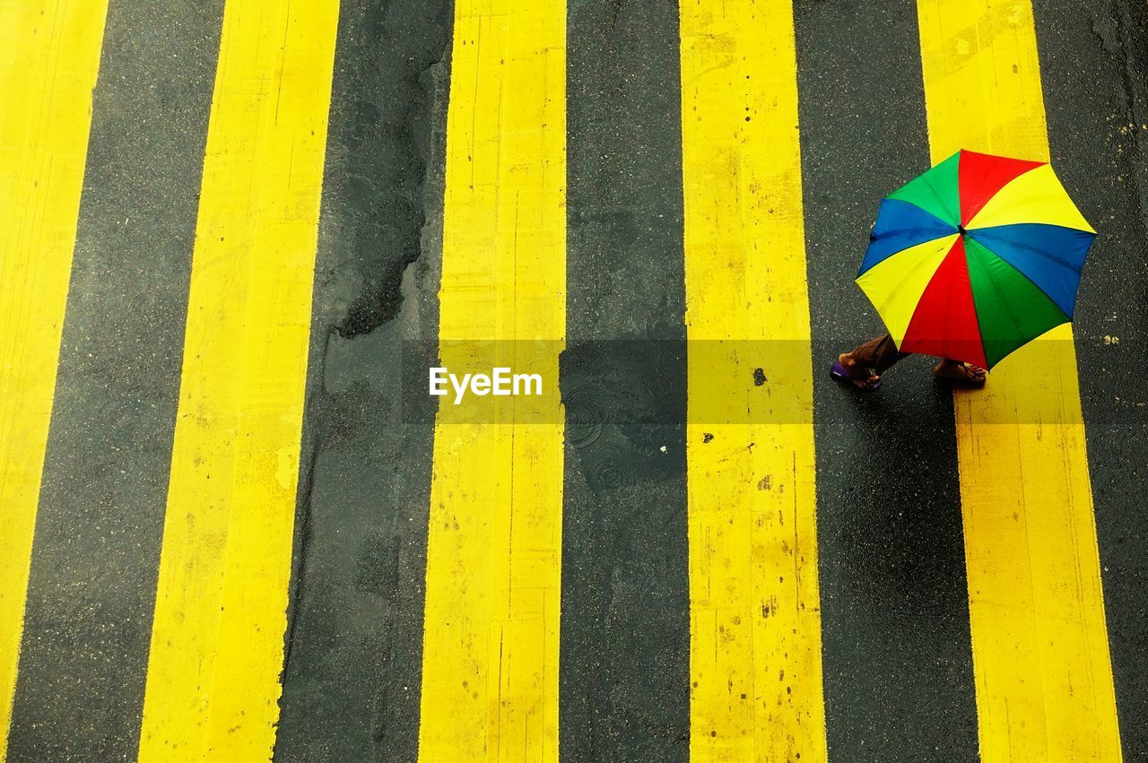 High angle view of man carrying multi colored umbrella while walking on street