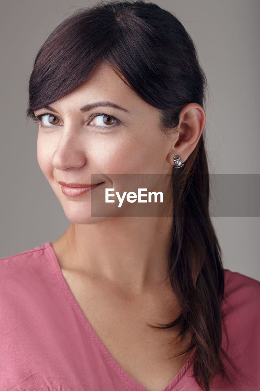 Portrait of beautiful woman against gray background