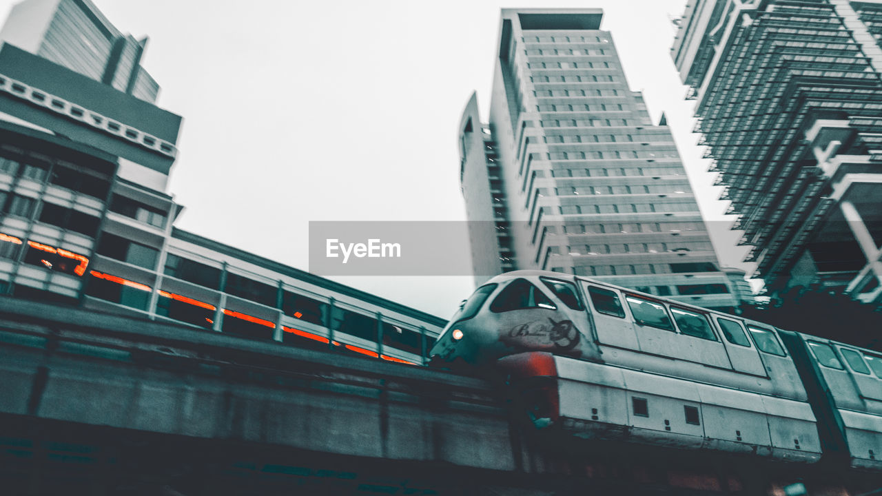 LOW ANGLE VIEW OF TRAIN AGAINST BUILDINGS