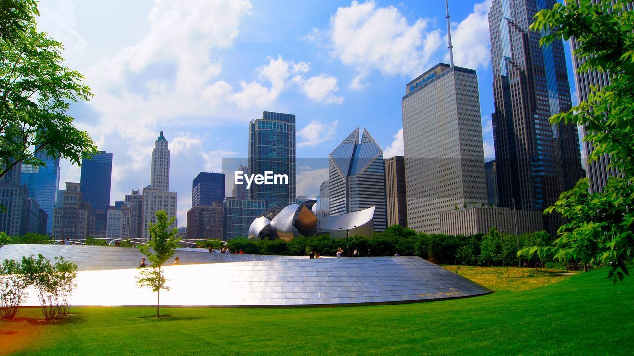 Scenic view of park by buildings against sky