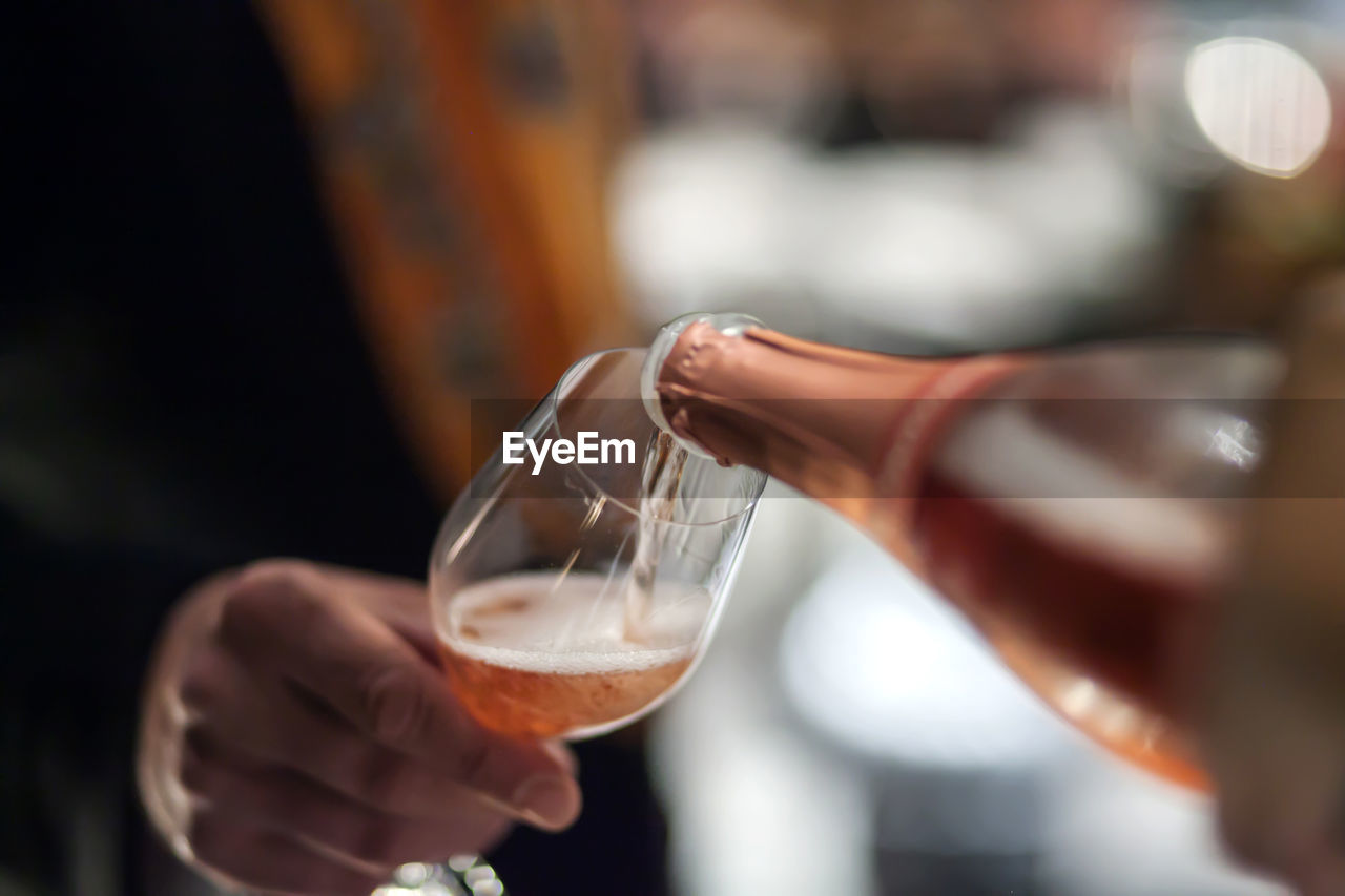 CLOSE-UP OF HAND POURING WINE GLASSES