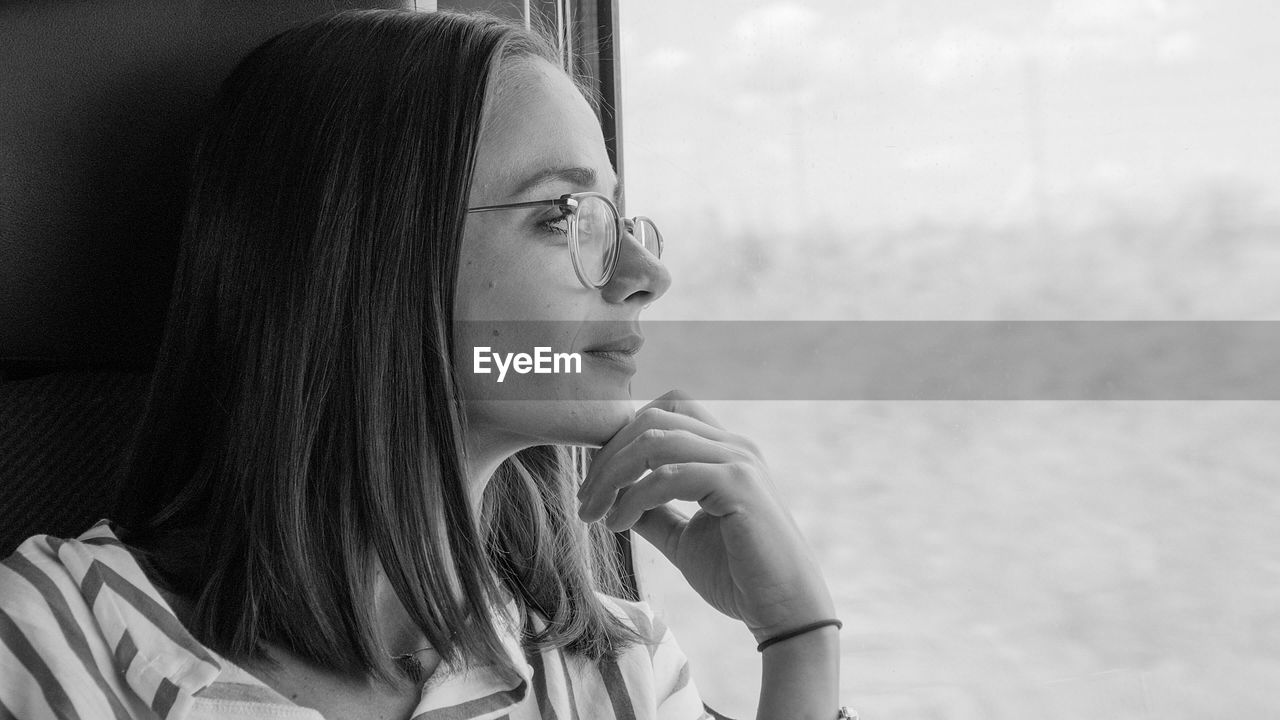 Woman looking through window while traveling in train