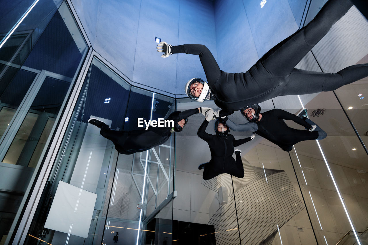 Athletes holding each others hands flying in wind tunnel