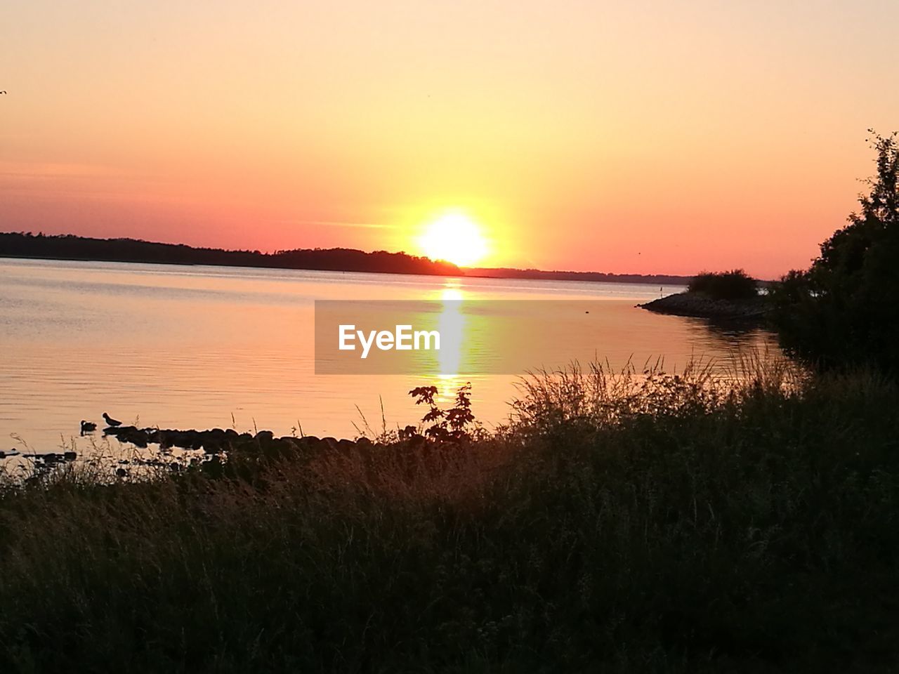 SCENIC VIEW OF LAKE AGAINST ORANGE SKY DURING SUNSET