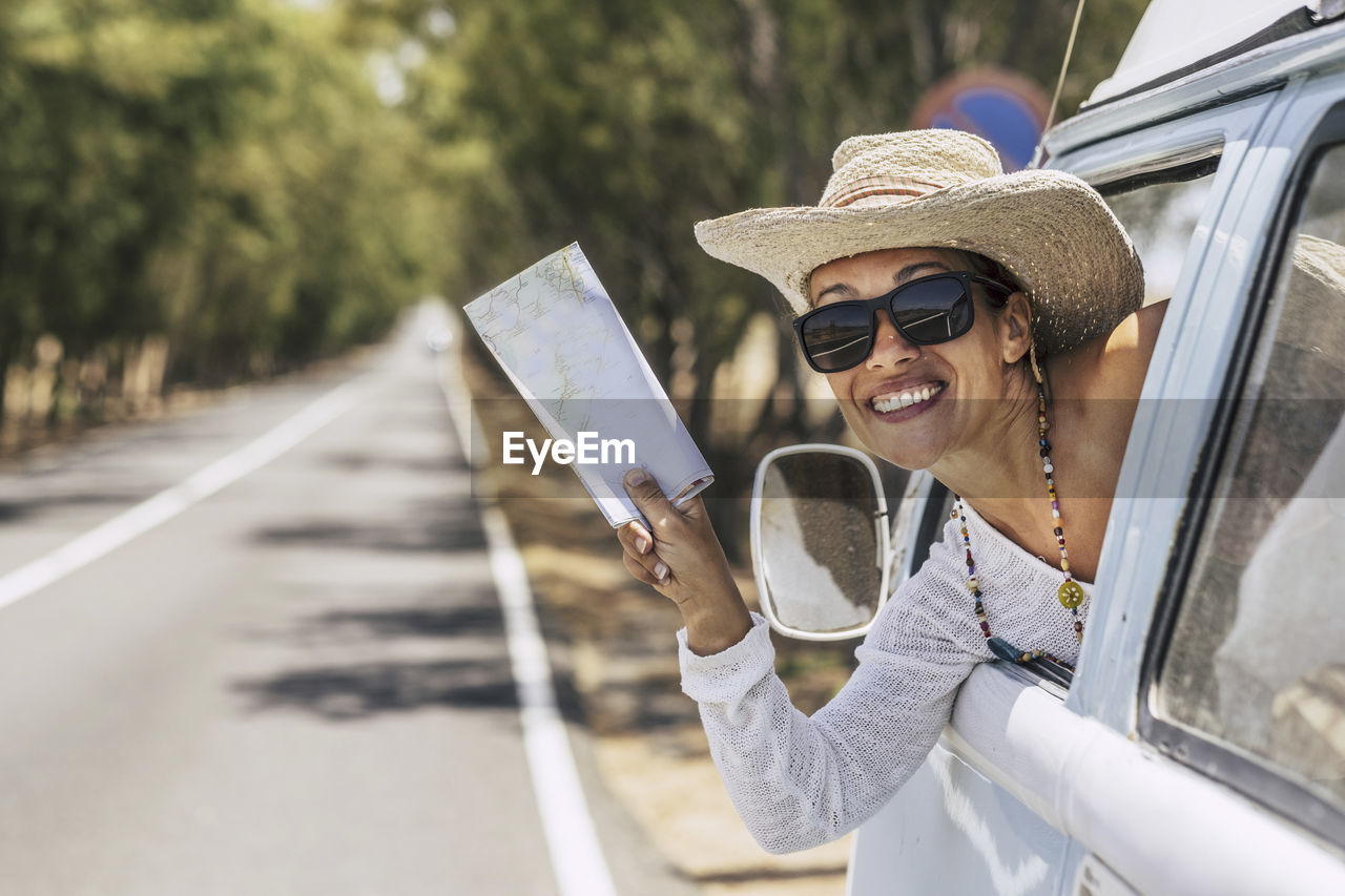 Portrait of smiling woman holding map in car