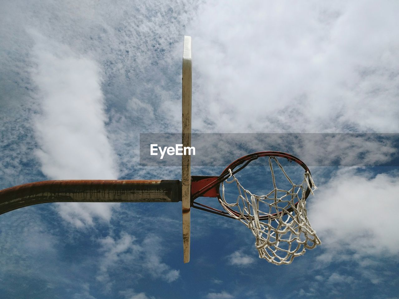 Low angle view of basketball hoop against cloudy sky