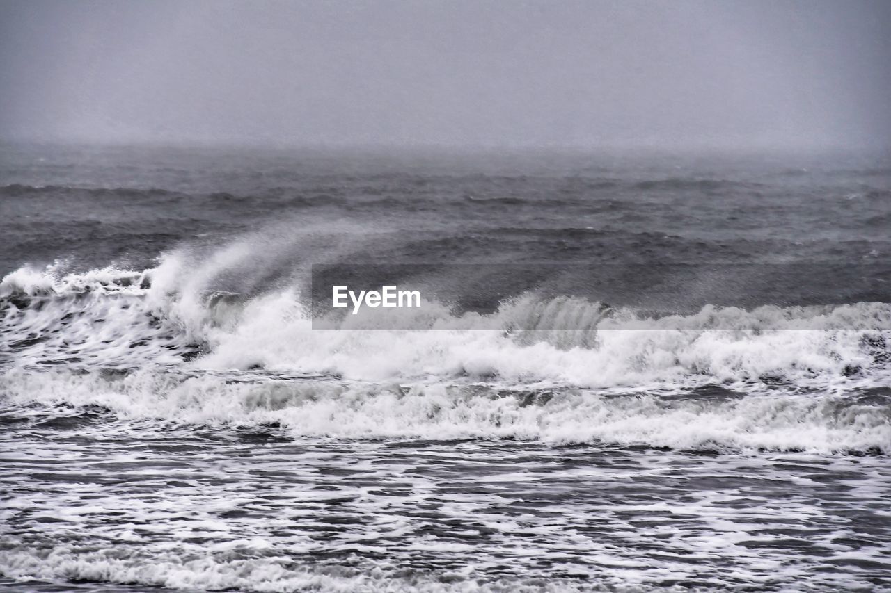 SCENIC VIEW OF SEA WAVES SPLASHING AGAINST SKY