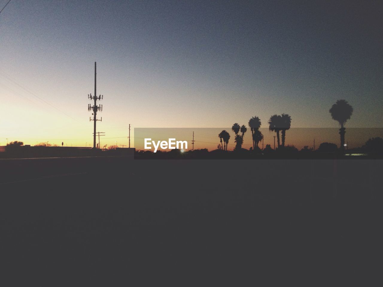 SILHOUETTE OF ELECTRICITY PYLONS AGAINST CLEAR SKY