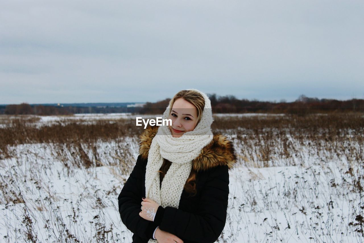 Portrait of woman standing on snow covered field