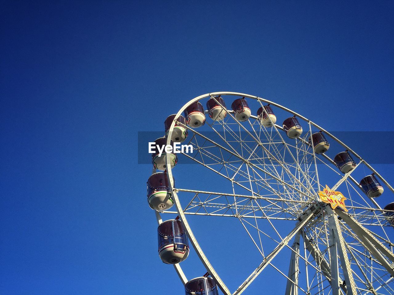 Low angle view of ferris wheel against clear blue sky