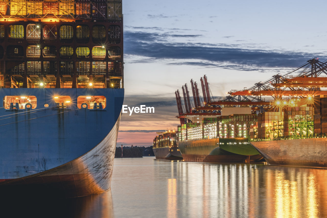 Germany, hamburg, container ships in port of hamburg at dusk