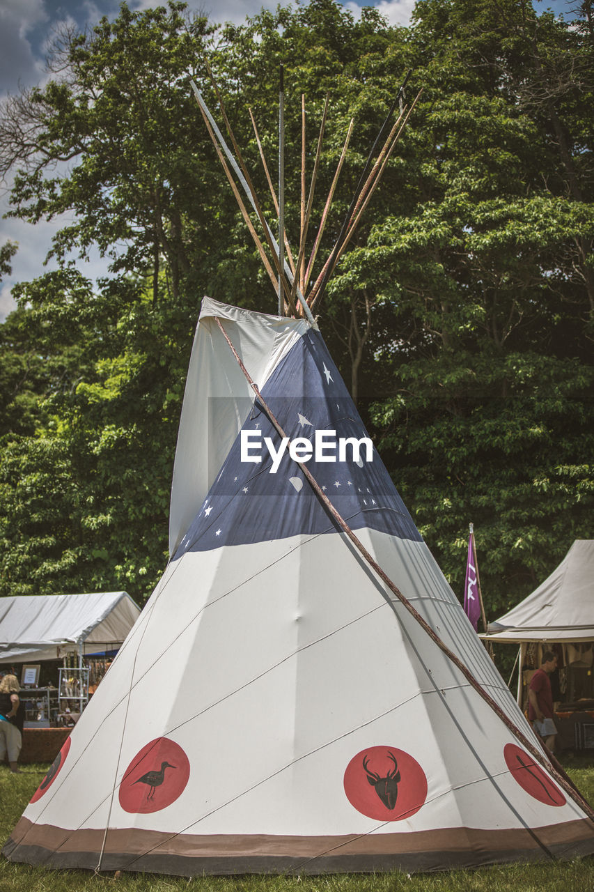 Old-fashioned tent on grassy field against trees at event