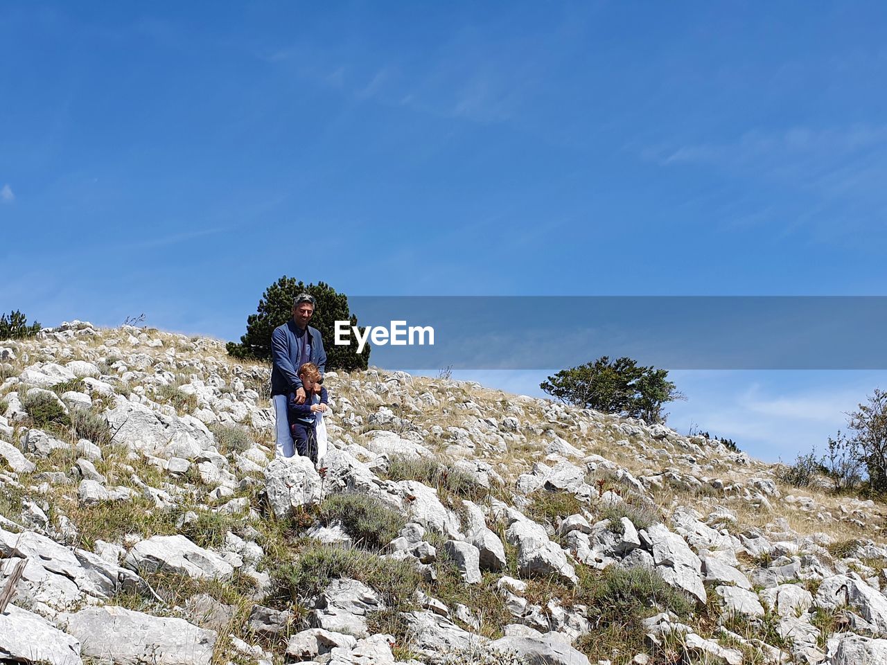 REAR VIEW OF MAN STANDING ON ROCK