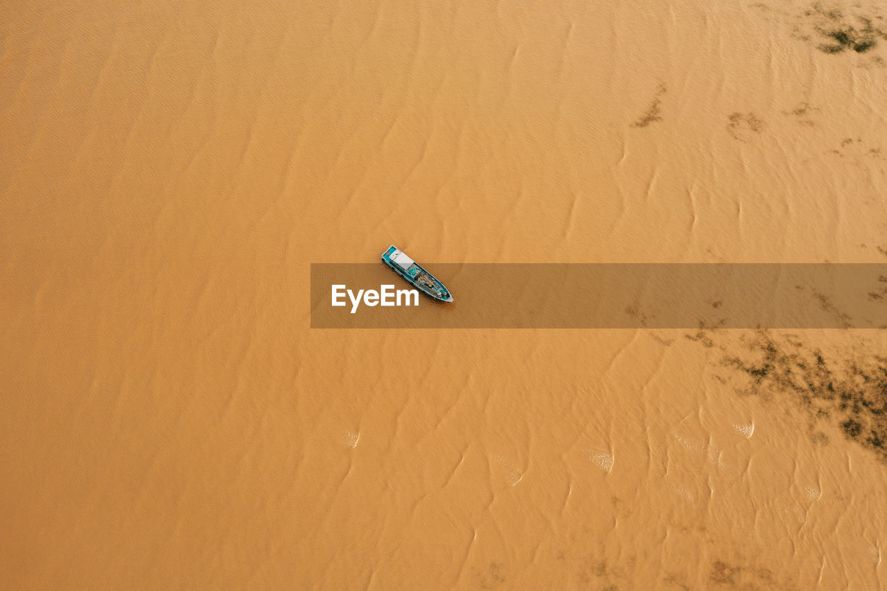HIGH ANGLE VIEW OF UMBRELLA ON SAND AT DESERT