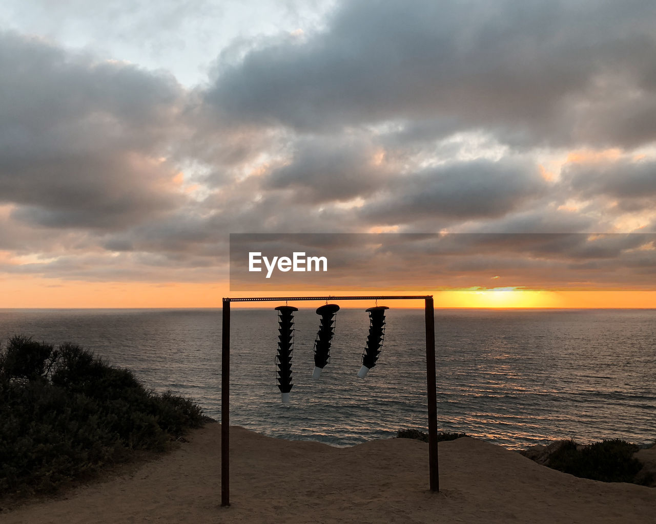 WOODEN POSTS IN SEA AGAINST SKY DURING SUNSET