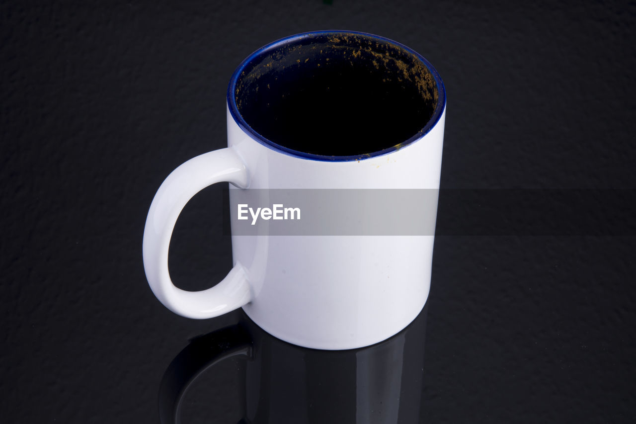 HIGH ANGLE VIEW OF COFFEE CUP ON TABLE AGAINST BLACK BACKGROUND