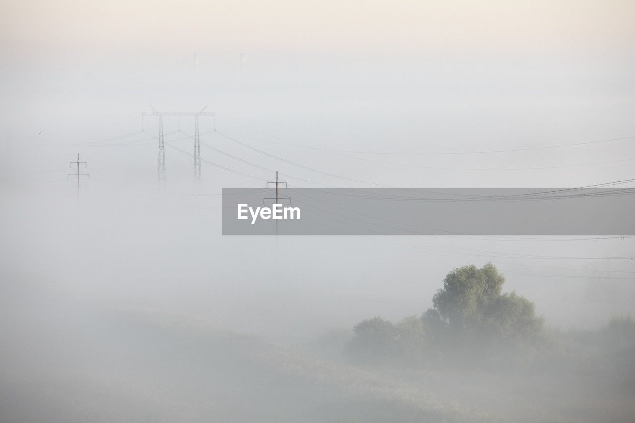 fog, cable, mist, electricity, haze, electricity pylon, technology, nature, environment, power line, power supply, beauty in nature, no people, scenics - nature, morning, tranquility, sky, winter, tree, land, landscape, tranquil scene, power generation, cold temperature, outdoors, snow, plant, day, non-urban scene, cloud, rural scene