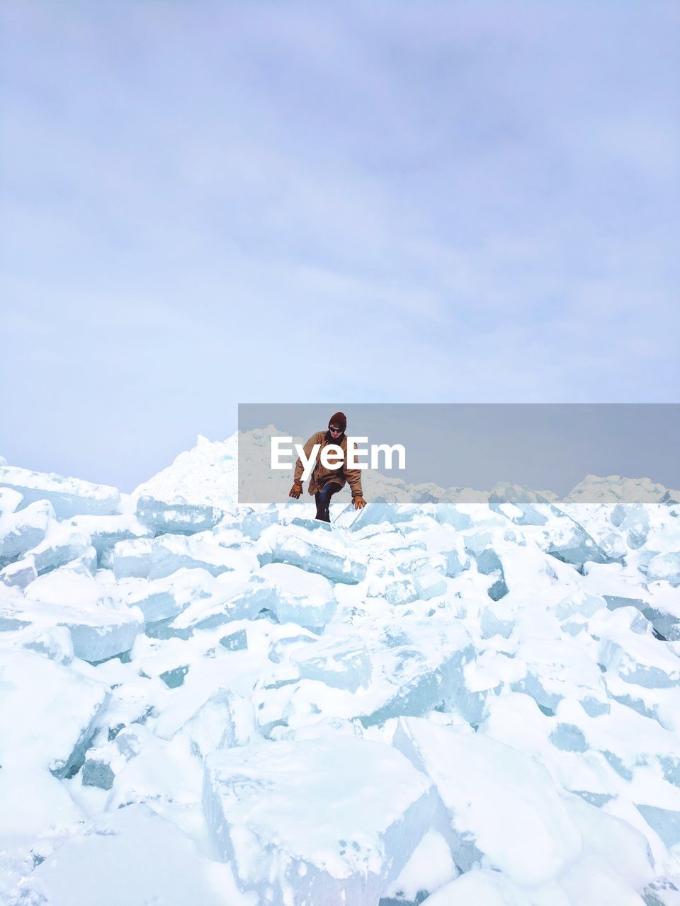 Young man walking on snowcapped mountains against clear sky