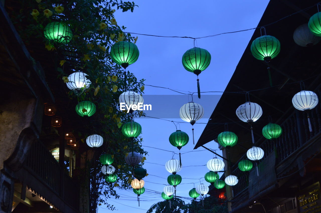 LOW ANGLE VIEW OF ILLUMINATED LANTERNS HANGING AGAINST CEILING