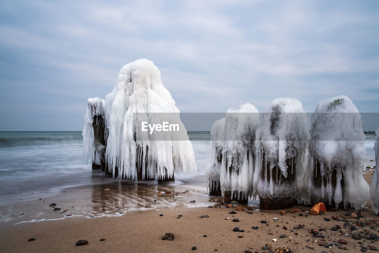 Close-up of frozen on beach against sky