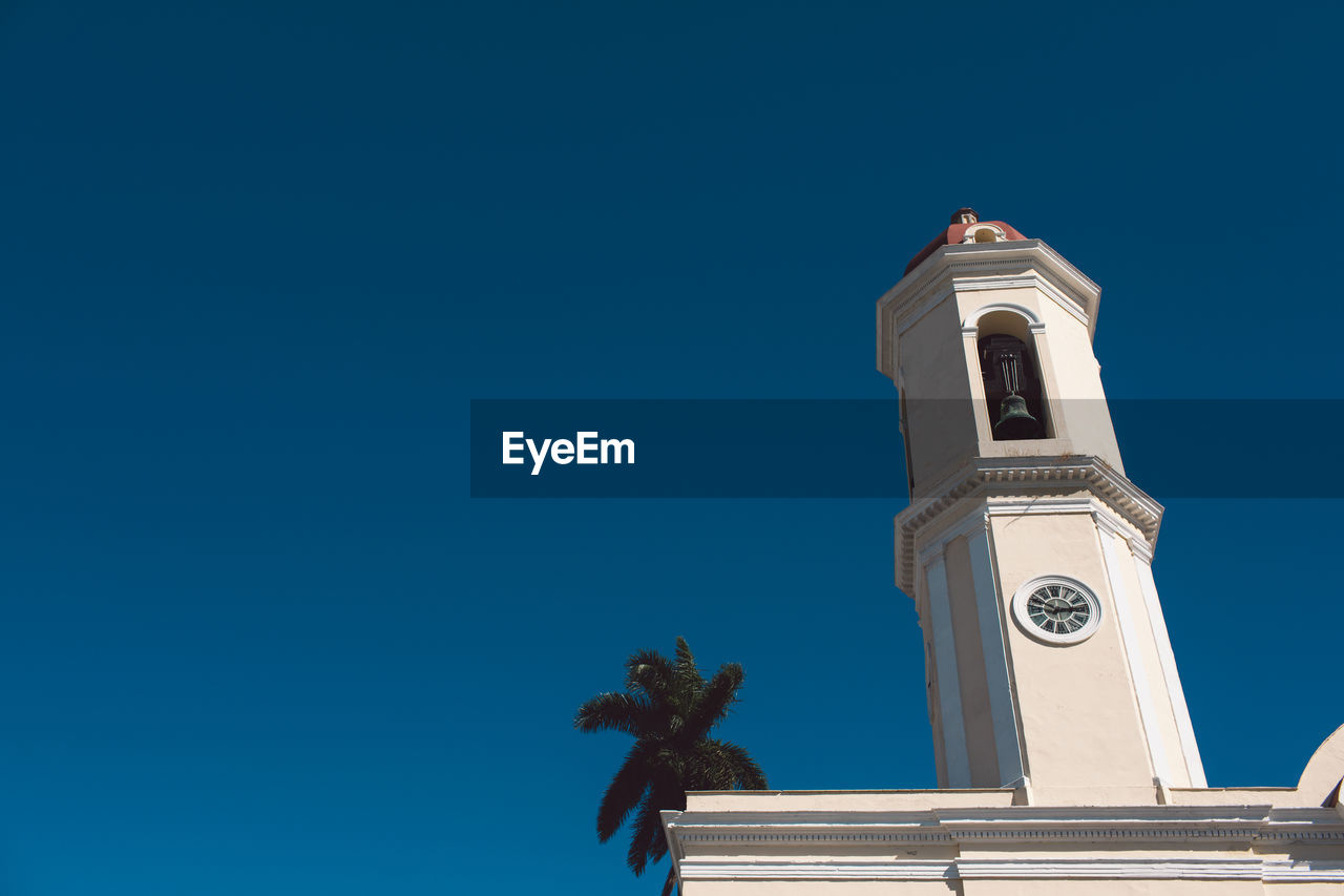 Low angle view of clock tower and building against clear blue sky