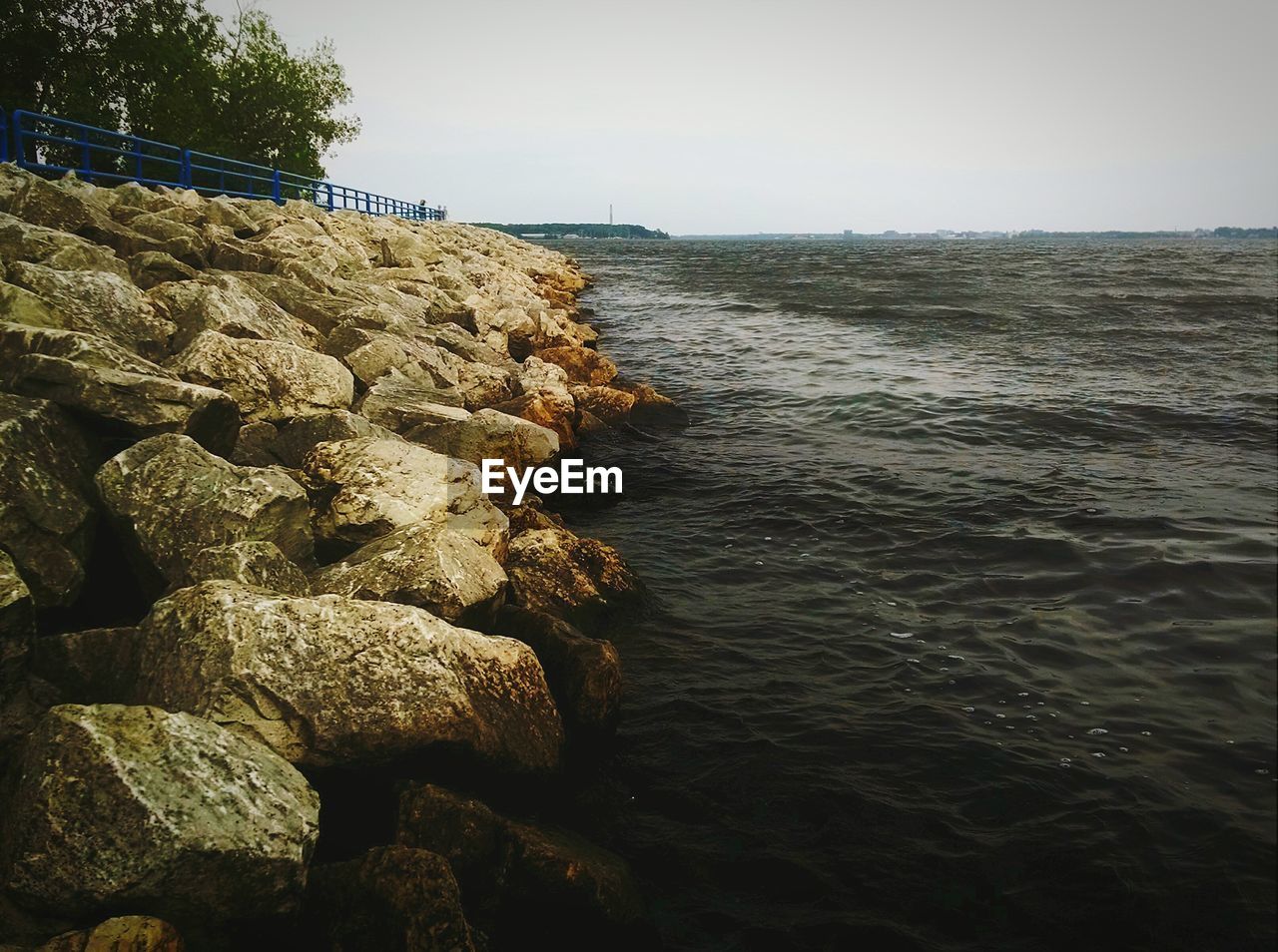 Scenic view of sea by rocks against clear sky