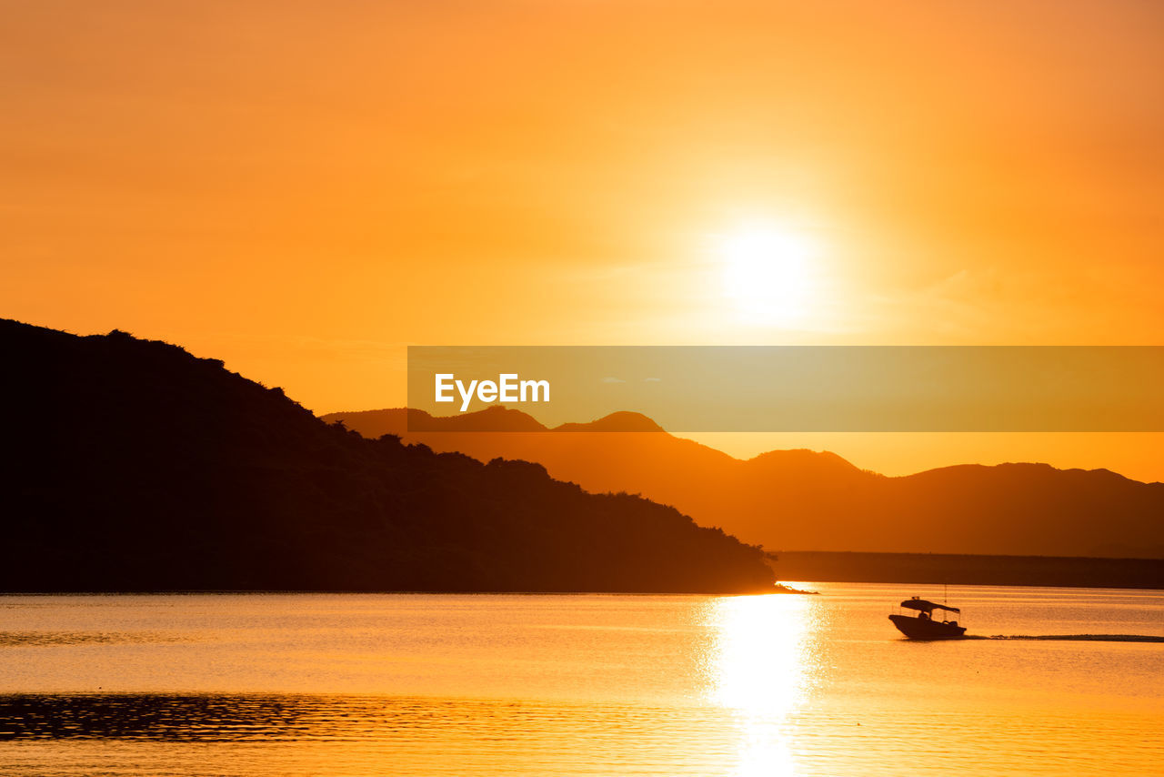 Scenic view of sea reflecting sunlight against golden orange sunrise sky