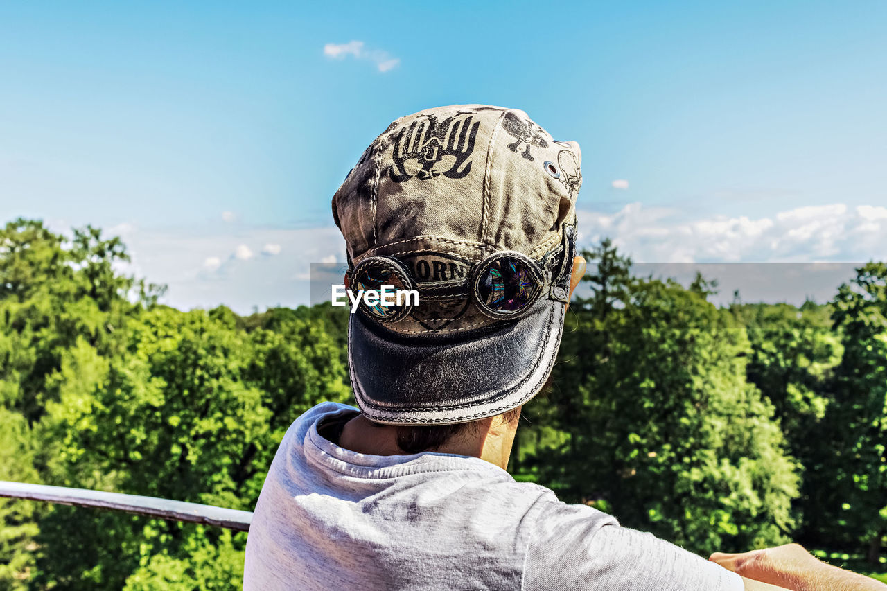 Rear view of person wearing cap looking at forest