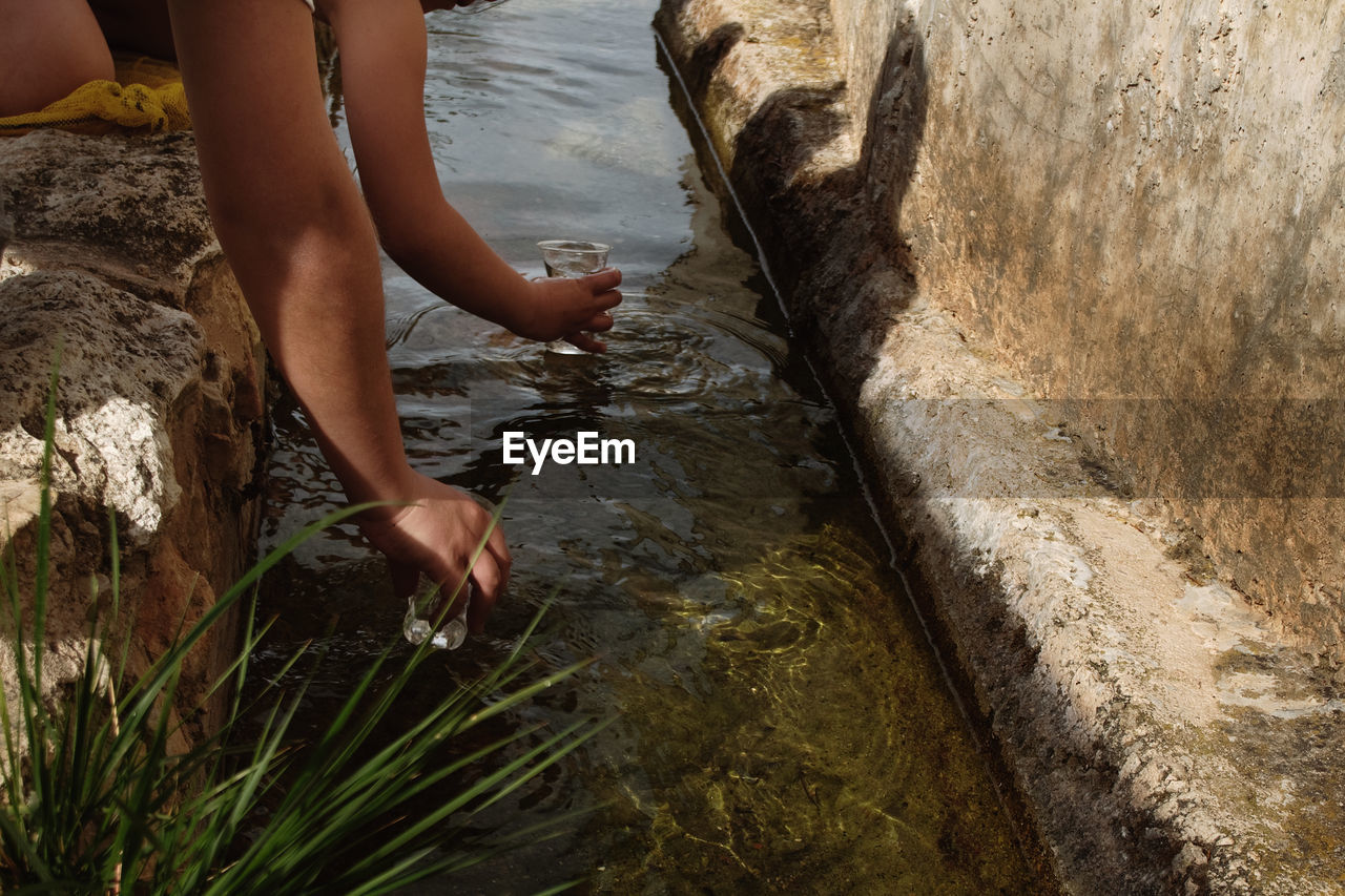 Cropped image of hands filling water from gutter