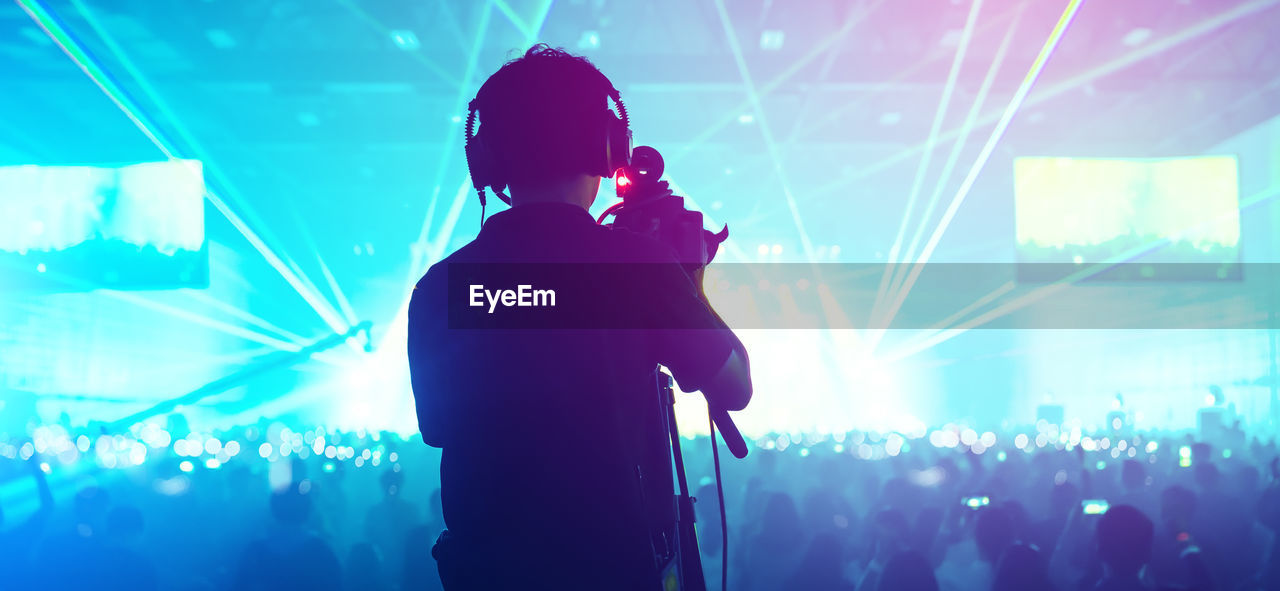 Rear view of man singing against crowd at music concert