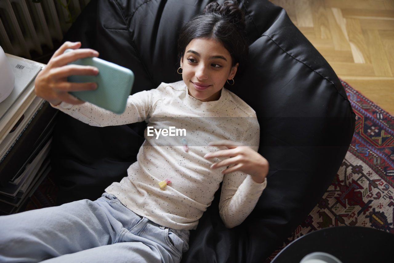 Girl lying on bean bag and taking selfie