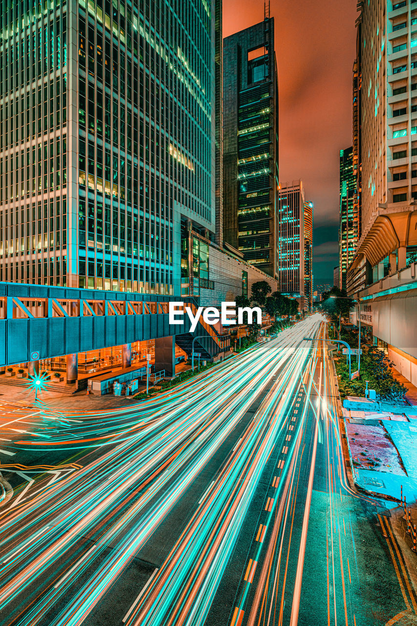 Light trails on city street amidst buildings