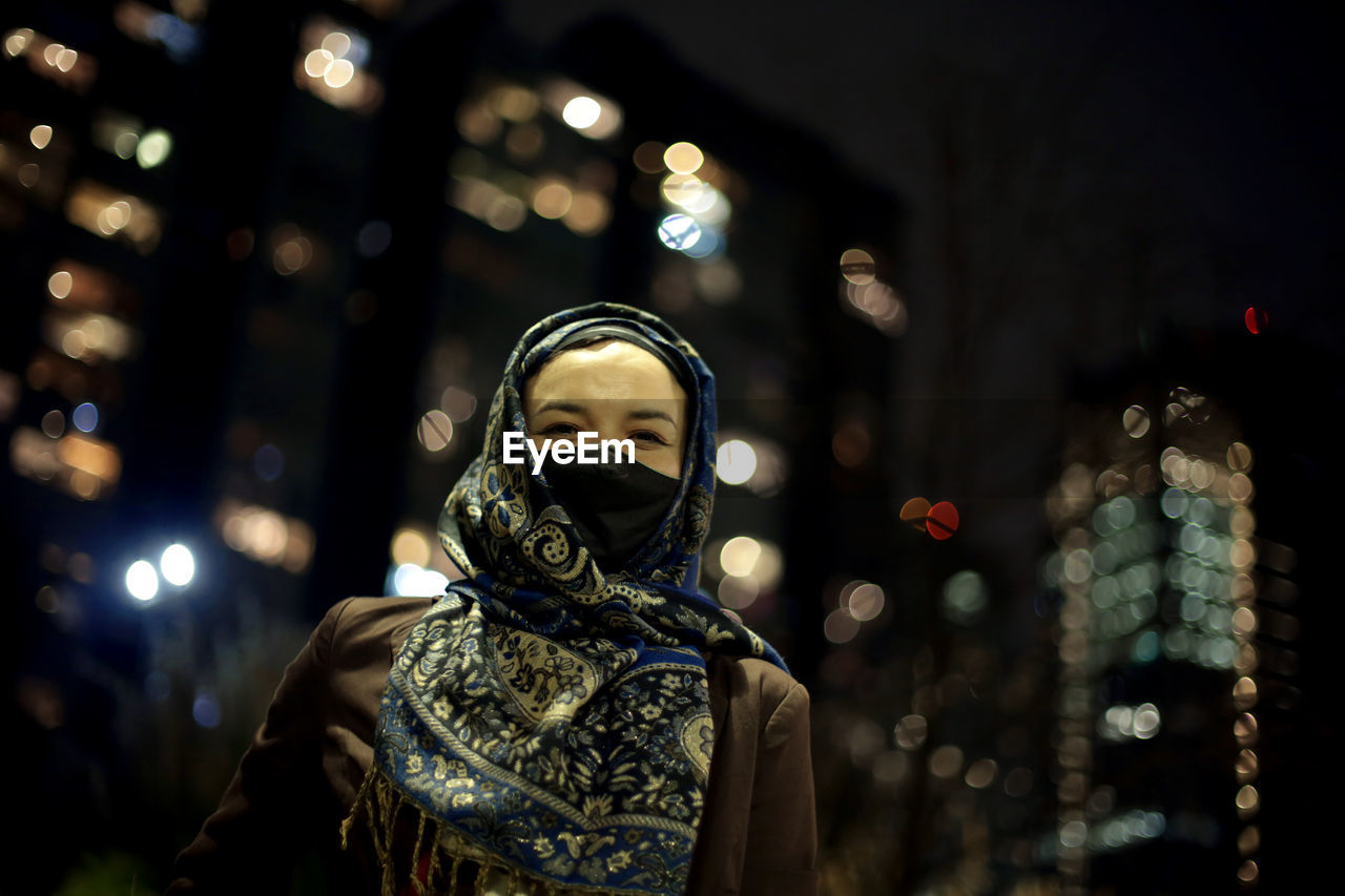 Low angle view of woman wearing hijab against city lights