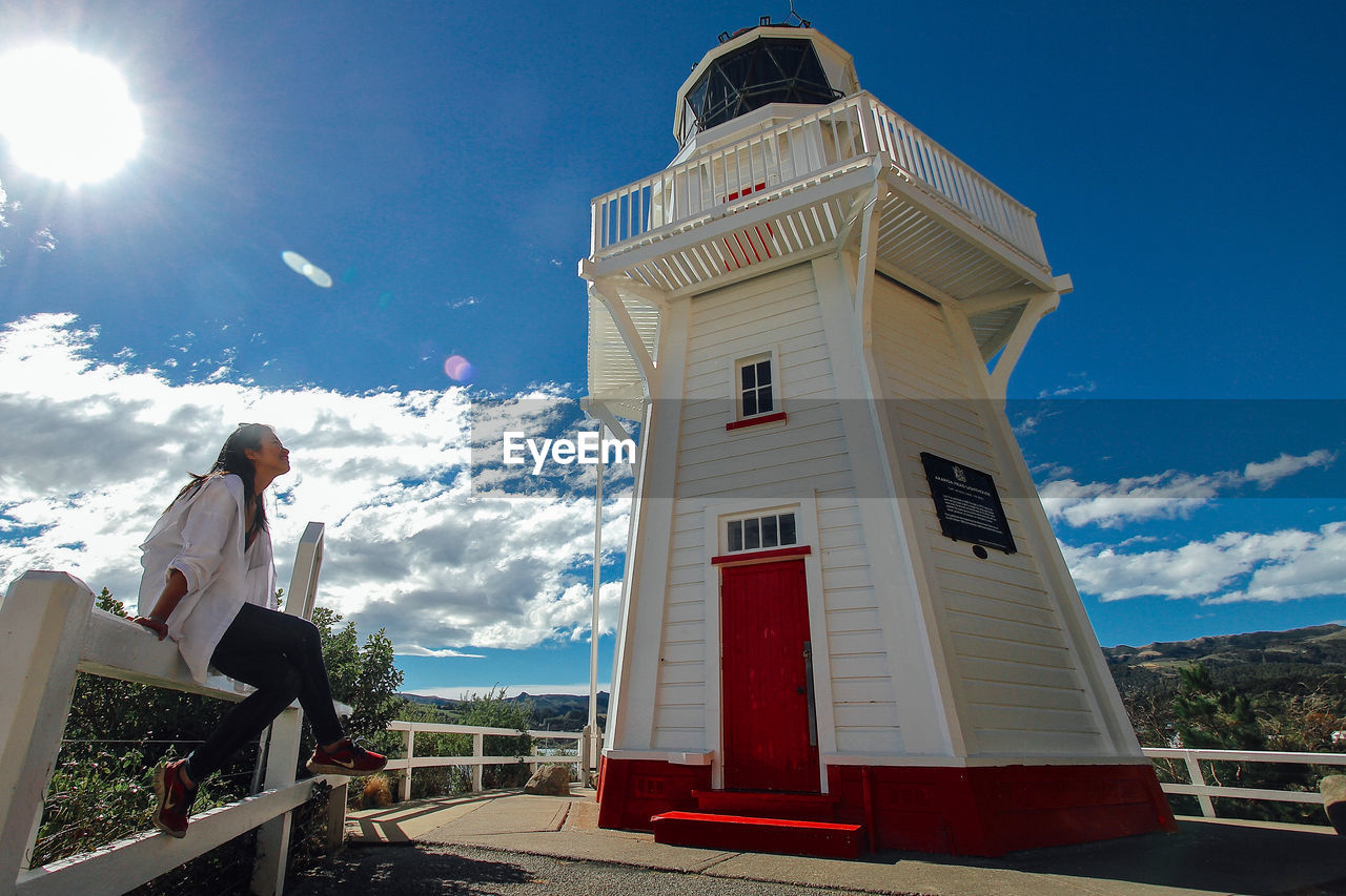 LOW ANGLE VIEW OF MAN STANDING BY BUILDING AGAINST SKY