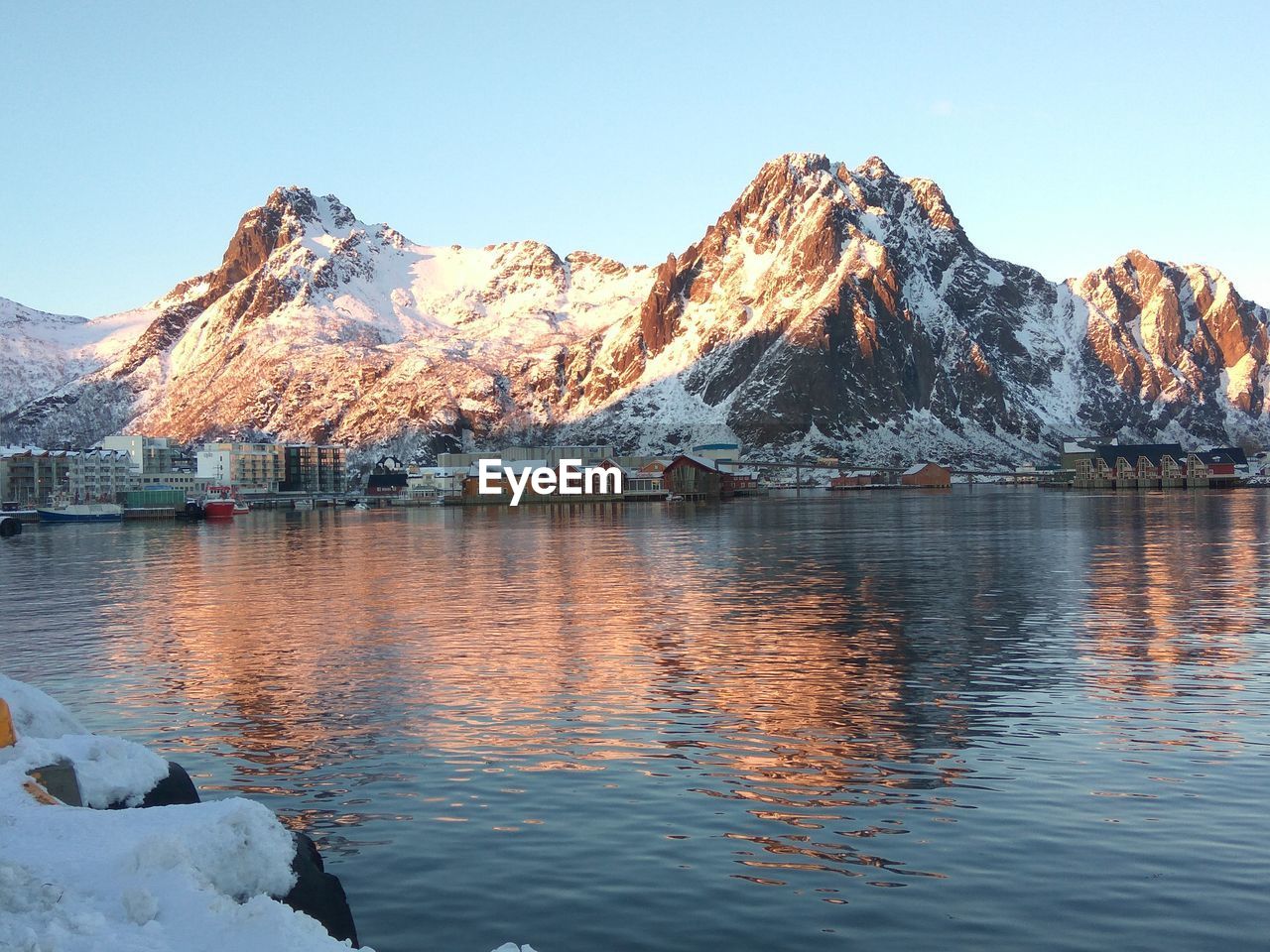 Scenic view of lake by snowcapped mountains against clear sky