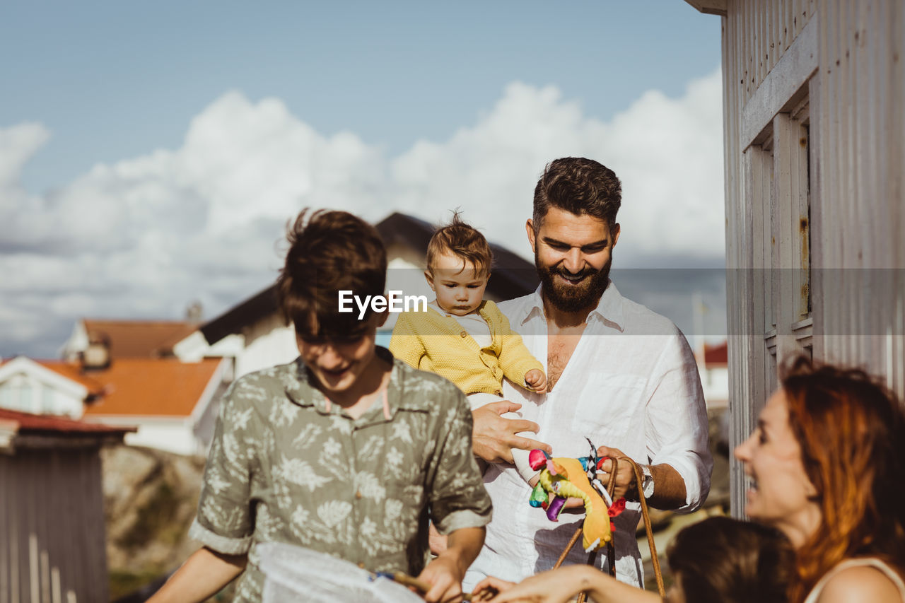 Happy father carrying daughter while family smiling by cabin