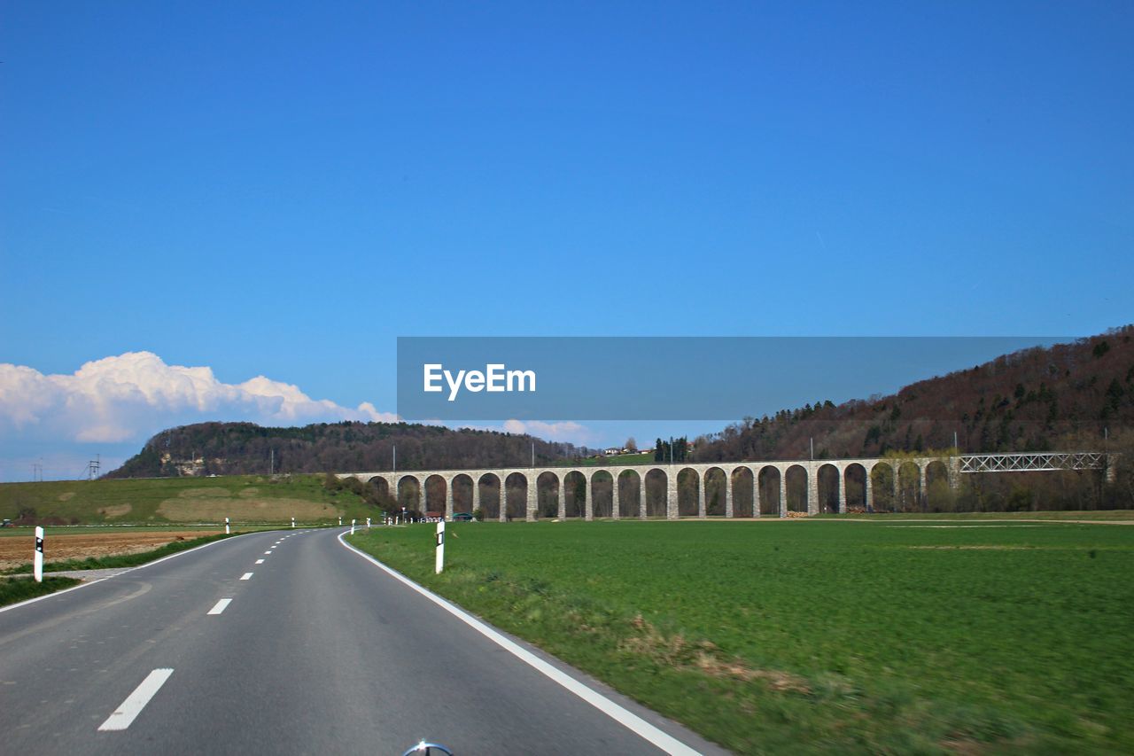 ROAD BY LANDSCAPE AGAINST BLUE SKY