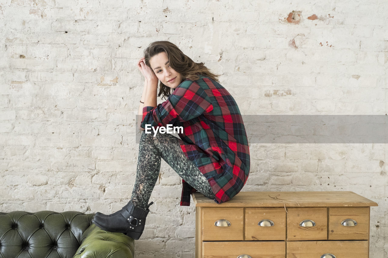 Portrait of a young woman sitting on a cabinet