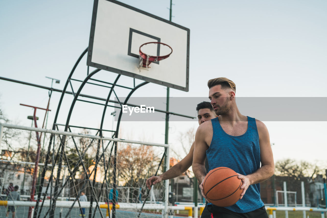 Men playing basketball against sky