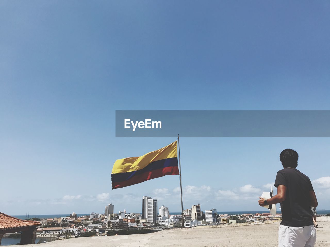 Rear view of man standing by colombian flag in city